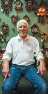 Howell Rust sits in front of an array of cuckoo clocks, the style his grandfather used to teach him the craft of horology.