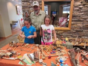 Sisters Caroline and Annabelle Ekern complete projects from the “Junior Ranger Activity Book” with old-time toymaker and park volunteer Joey Beason at Cumberland Gap National Historical Park. Photograph Courtesy of the National Park Service