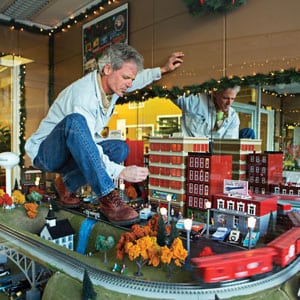 Bill Fann carefully balances between the toy tracks as he puts the finishing touches on the holiday display.