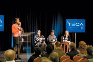 Youth Leadership Council representative Denisha Patrick addresses the annual meeting. Seated are statewide Washington Youth Tour Writing Contest scholarship winners, from left, Sarah Terry, Kai Starmer and Emily Fleeman.