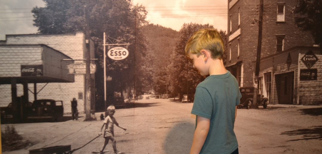 A young visitor to the Butler Museum waves to the photo of a boy named Russell Mink pulling his wagon through Butler in 1947. (Tennessee History for Kids photo)