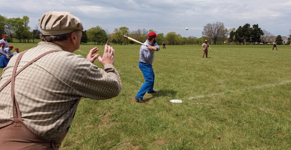 A Lightfoot ballist is at bat as Distiller Rick “Big Red” Brooks catches. Each vintage bat is hand-crafted by Smacker Bats of Murfreesboro. The company has been making bats according to early base ball specifications for 20 years. 