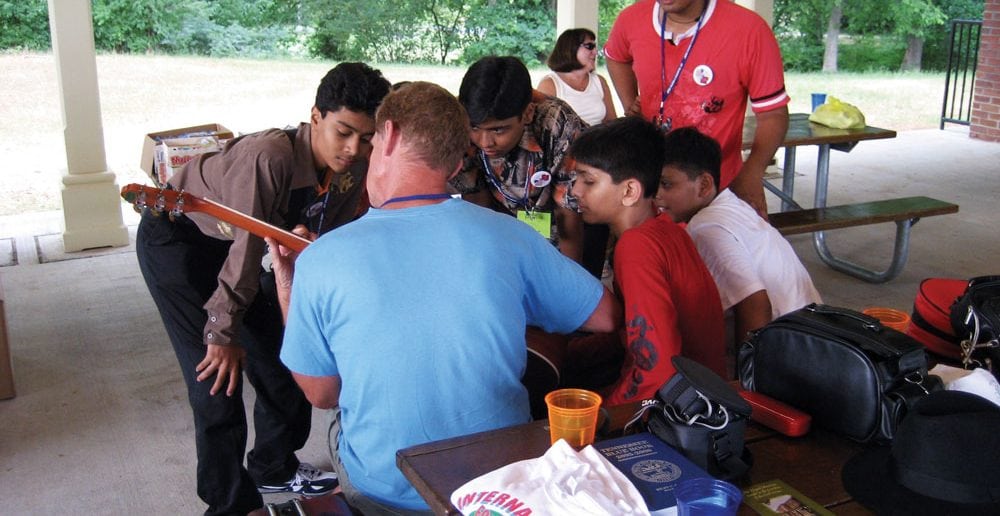 Young men from an Indian folk troupe performing at the FolkFest are fascinated by a Tennessee musician.