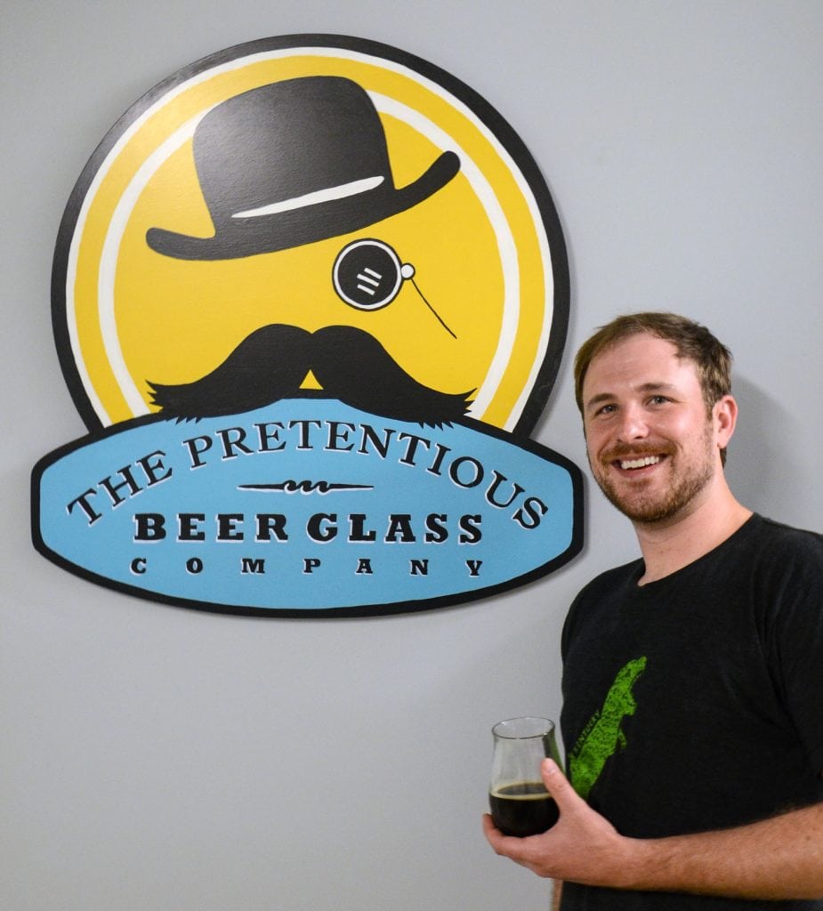 Matthew Cummings holds one of the products he makes for the glass company he founded to serve the growing craft beer industry. Photo courtesy of Matthew Cummings