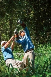 Jerry Fishburn and Luke Flory manually pull wire back up to Kirk Harris in the bucket.